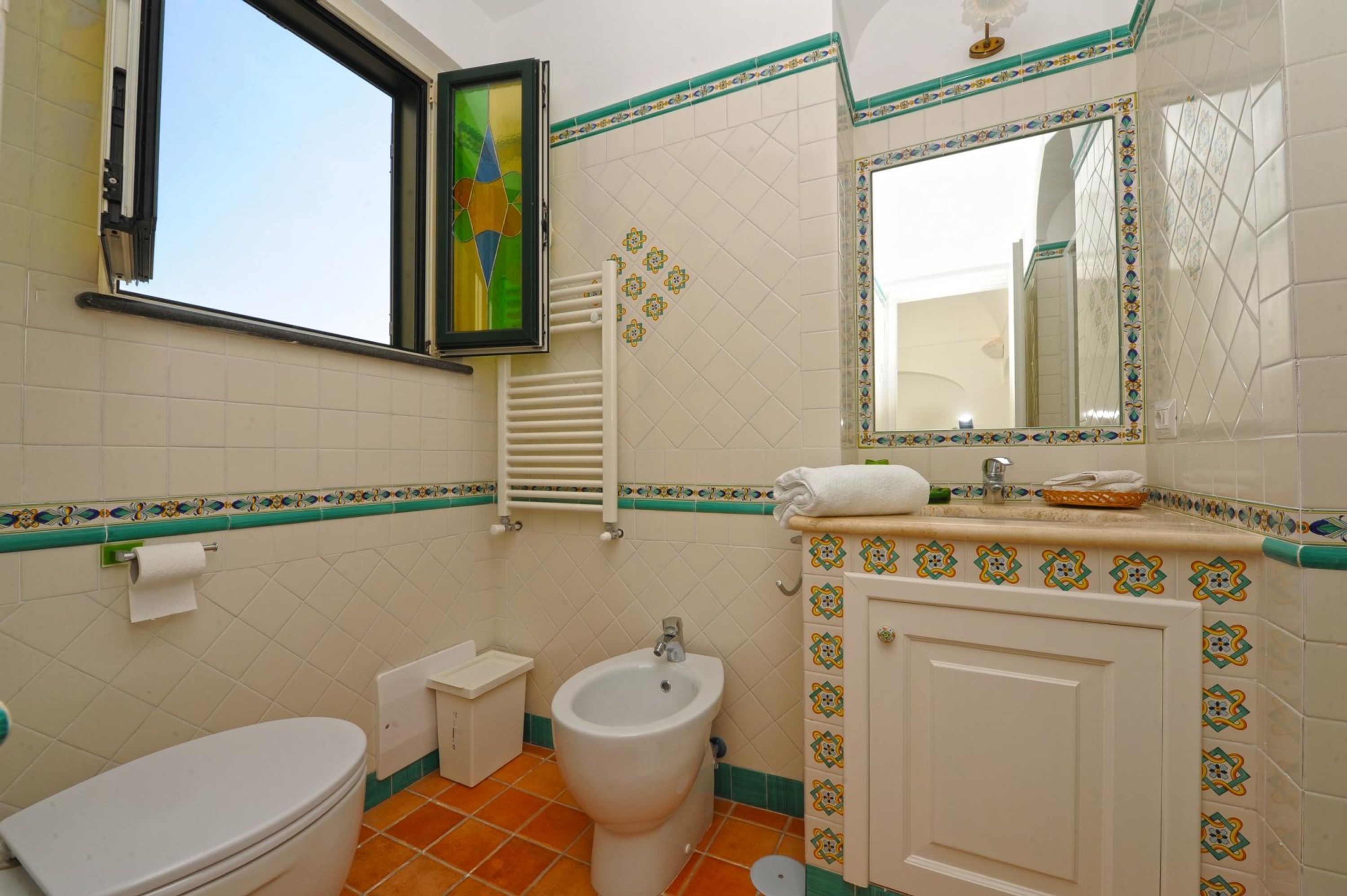 A bathroom with a toilet, bidet, sink, and a mirror.