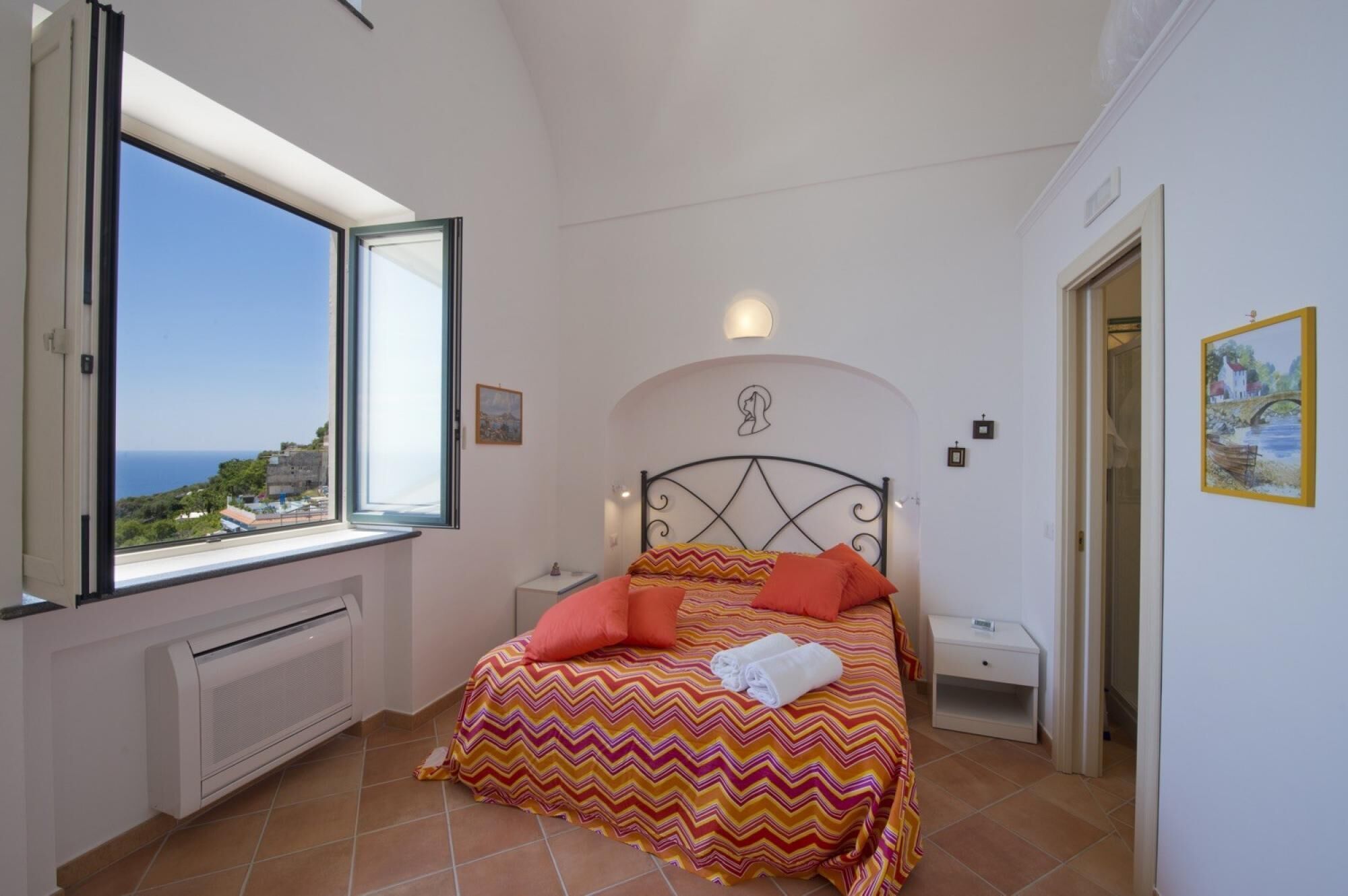 Quarto com cama, radiador, mesa de cabeceira e um quadro na parede.