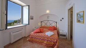 A bedroom with a bed, a radiator, a nightstand, and a painting on the wall. - Casa Giorgia - Exclusive Panoramic Villa in the Heart of Praiano (Praiano)