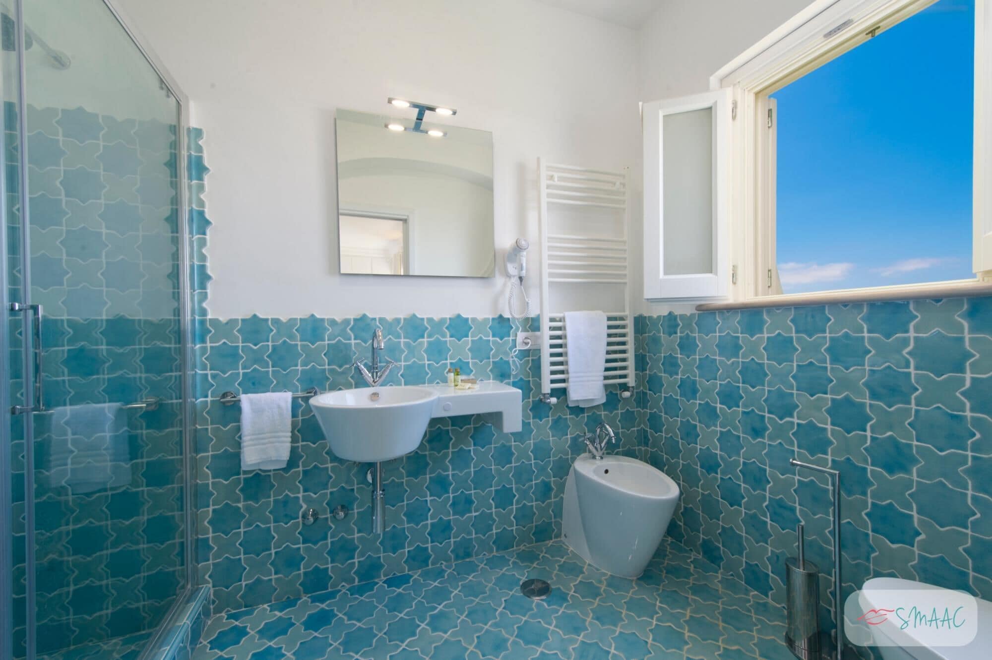 Une salle de bain avec une douche, deux lavabos, des toilettes et une fenêtre donnant sur un beau paysage.