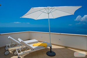 A balcony with a white umbrella, a white sun lounger, and a view of the sea. - Villa Imperati - Splendid Villa With Private Pool Overlooking the sea (Praiano)