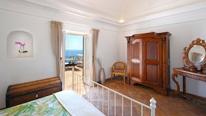 Ein Schlafzimmer mit Balkon, einem Holzschrank, einem Stuhl und einem Spiegel.