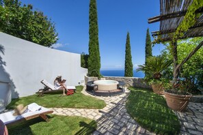 Une terrasse avec un jacuzzi, un fauteuil de relaxation et une personne qui lit.