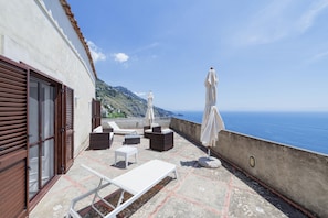 A rooftop terrace with outdoor seating, including a sun lounger and chairs, overlooking a coastal view. - Villa Panorama - Garden Overlooking the sea and Sauna (Praiano)
