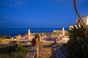 An outdoor seating area with tables and chairs, overlooking a body of water. - Villa Panorama - Garden Overlooking the sea and Sauna (Praiano)