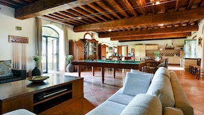 A spacious living room with a pool table, a sofa, and a dining area with a kitchen in the background. - Rosmarino Apartment With two Bedrooms and one Bathroom on the Ground Floor Apartment 1 (Longare)