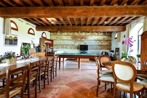 A cozy room with a pool table, wooden furniture, stone wall, and a television.
