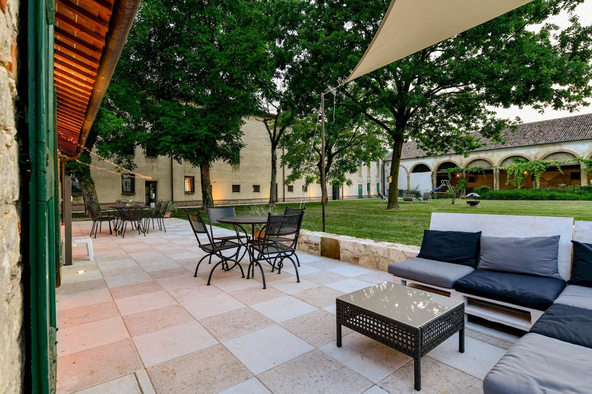 A courtyard with outdoor seating, including a table and chairs, and a sofa.
