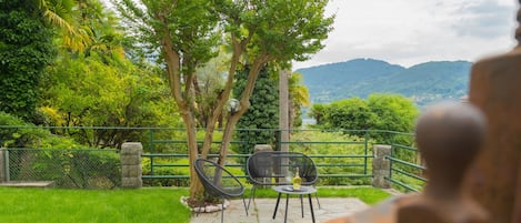 Un patio exterior con vistas a un paisaje montañoso, una mesa con sillas y una escultura decorativa.