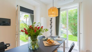 Eine moderne Küche mit Essbereich, einer Vase mit roten Tulpen und Blick auf den Garten durch die Glastür.