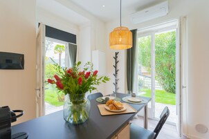 Una cocina moderna con comedor, un jarrón de tulipanes rojos y vistas al jardín a través de la puerta de vidrio.