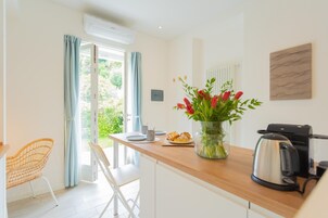 Una cocina moderna con encimera de madera, una cafetera y un florero con flores rojas.