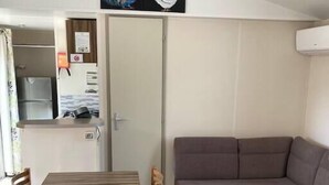 Un espacio habitable compacto con una mesa de comedor, sillas, un sofá y una pequeña mesita de madera.