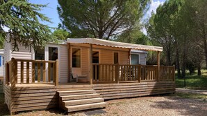 Una cabaña de madera con un porche, una silla y una pequeña terraza.