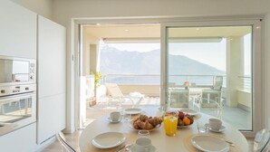 Un comedor con una mesa dispuesta para el desayuno, incluyendo platos, tazas y una cesta con cruasanes.