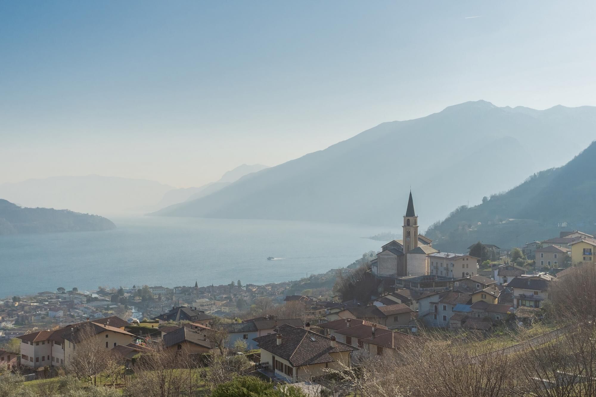 A coastal town with a prominent church, surrounded by mountains and a body of water.