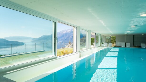 Una amplia piscina interior con vistas despejadas a montañas y un lago.