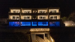Un edificio moderno de varios pisos con ventanas iluminadas y un acceso cubierto.