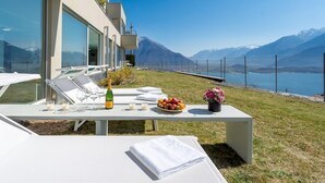 Una terraza con una mesa lista para una comida, con vistas a un lago y montañas.