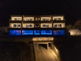 Un edificio moderno de varios pisos con balcones iluminados y una entrada cubierta.
