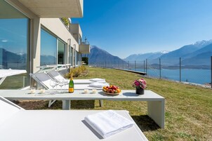 Una terraza con una mesa dispuesta para comer, con vistas a un lago y montañas.