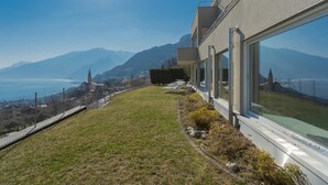 Un bâtiment moderne doté de grandes fenêtres donnant sur un paysage montagneux et un plan d’eau.
