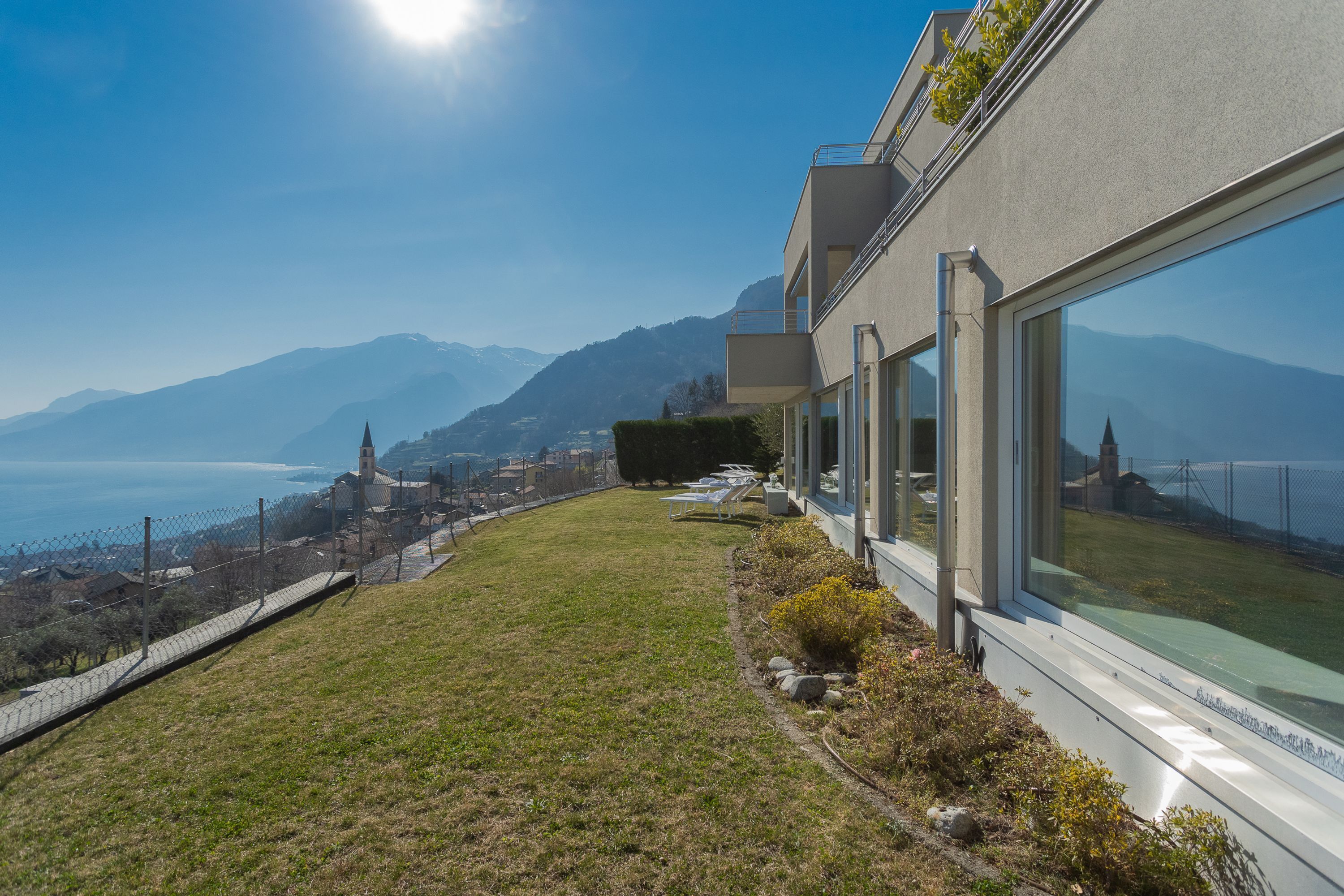 A modern building with large windows overlooking a mountainous landscape and a body of water.