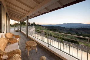 A balcony with wicker furniture, a view of rolling hills, and a clear sky. - Villa Ambretta in Campagnatico (Campagnatico)