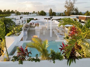 A rooftop pool area with a view of the ocean, surrounded by palm trees and modern outdoor furniture. - New York Times featured this Beachfront Penthouse w/Dior inspired Rooftop & Pool (Las Terrenas)