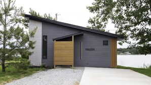 Een modern gebouw met een grijze gevel en een houten deur waarop 