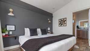 Een moderne slaapkamer met een groot bed, nachtkastjes en een klein bureau.