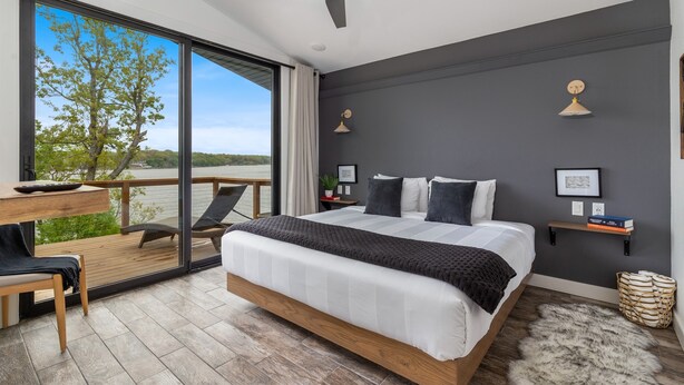 Een moderne slaapkamer met een groot bed, een bureau en een balkon met uitzicht op de omgeving.