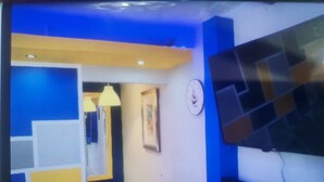 Een gang met blauwe en gele wanden, een klok en een televisie.