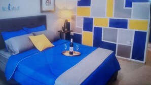 Een slaapkamer met een bed, nachtkastje, lamp en een muur met een geometrisch patroon.