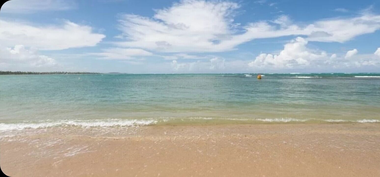 Una spiaggia con acque turchesi cristalline, una riva sabbiosa e un orizzonte lontano.