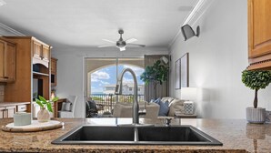 A kitchen with granite countertops, wooden cabinets, a double sink, and a ceiling fan. - Comfy 1-Bedroom, 2-Bath Condo in Gated Community - Includes 3 Adult Bikes! (Santa Rosa Beach)