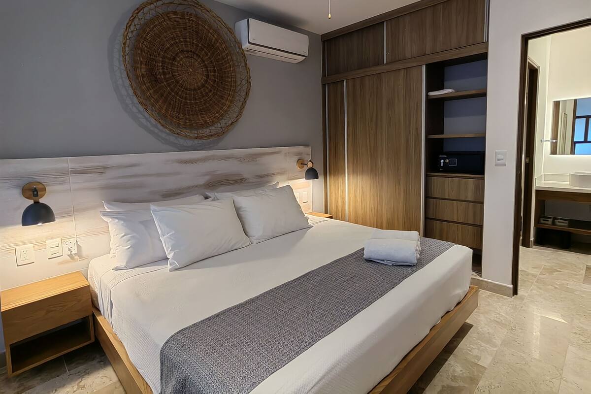 A modern bedroom with a large bed, a wooden wardrobe, and a ceiling fan.