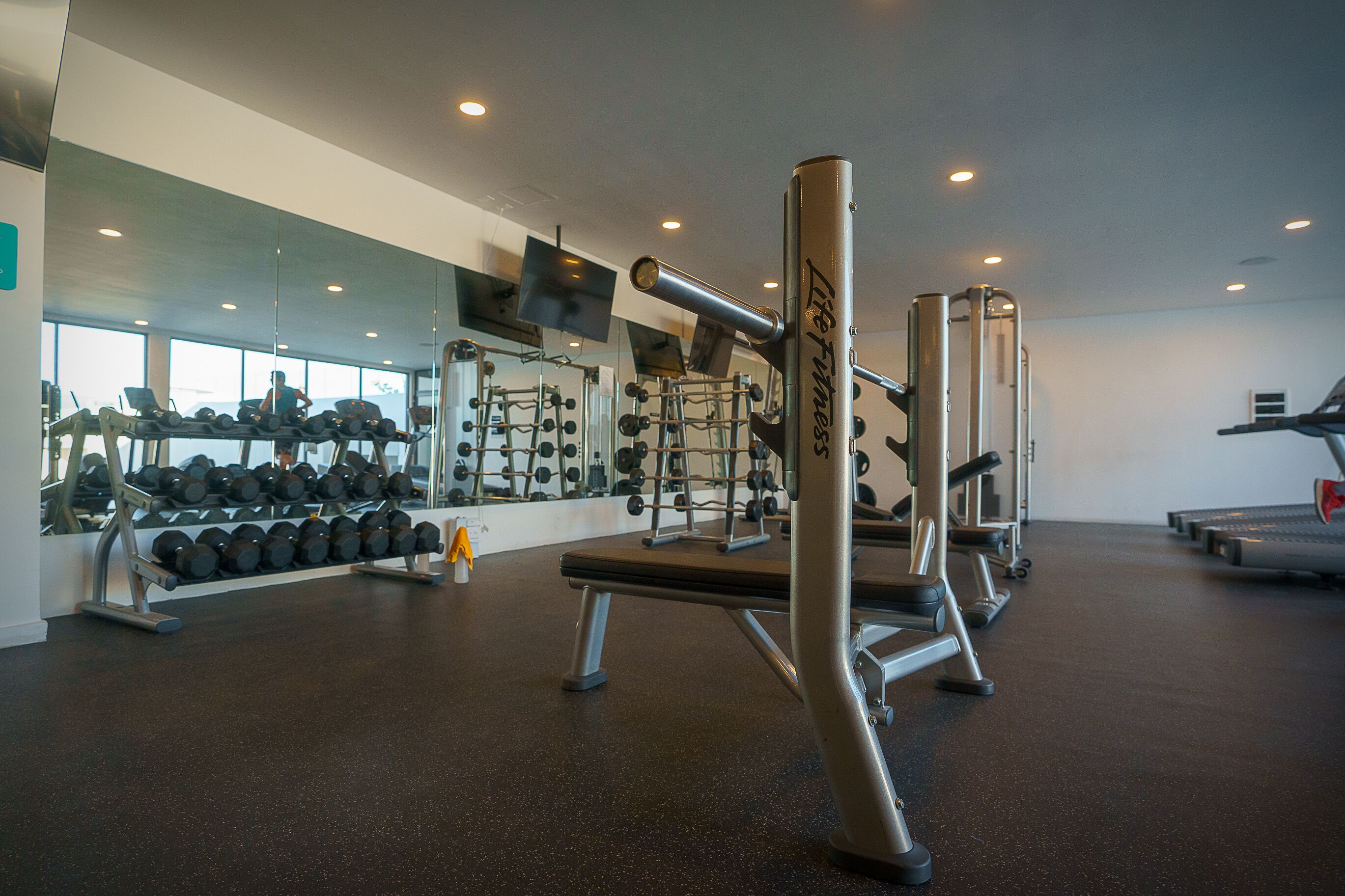 A gym with weightlifting equipment, dumbbells, and exercise machines.