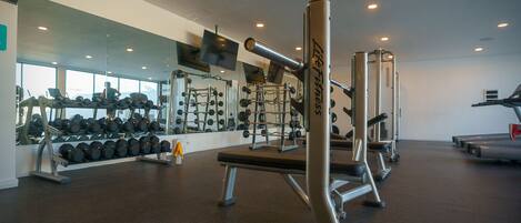 A gym with weightlifting equipment, dumbbells, and exercise machines.