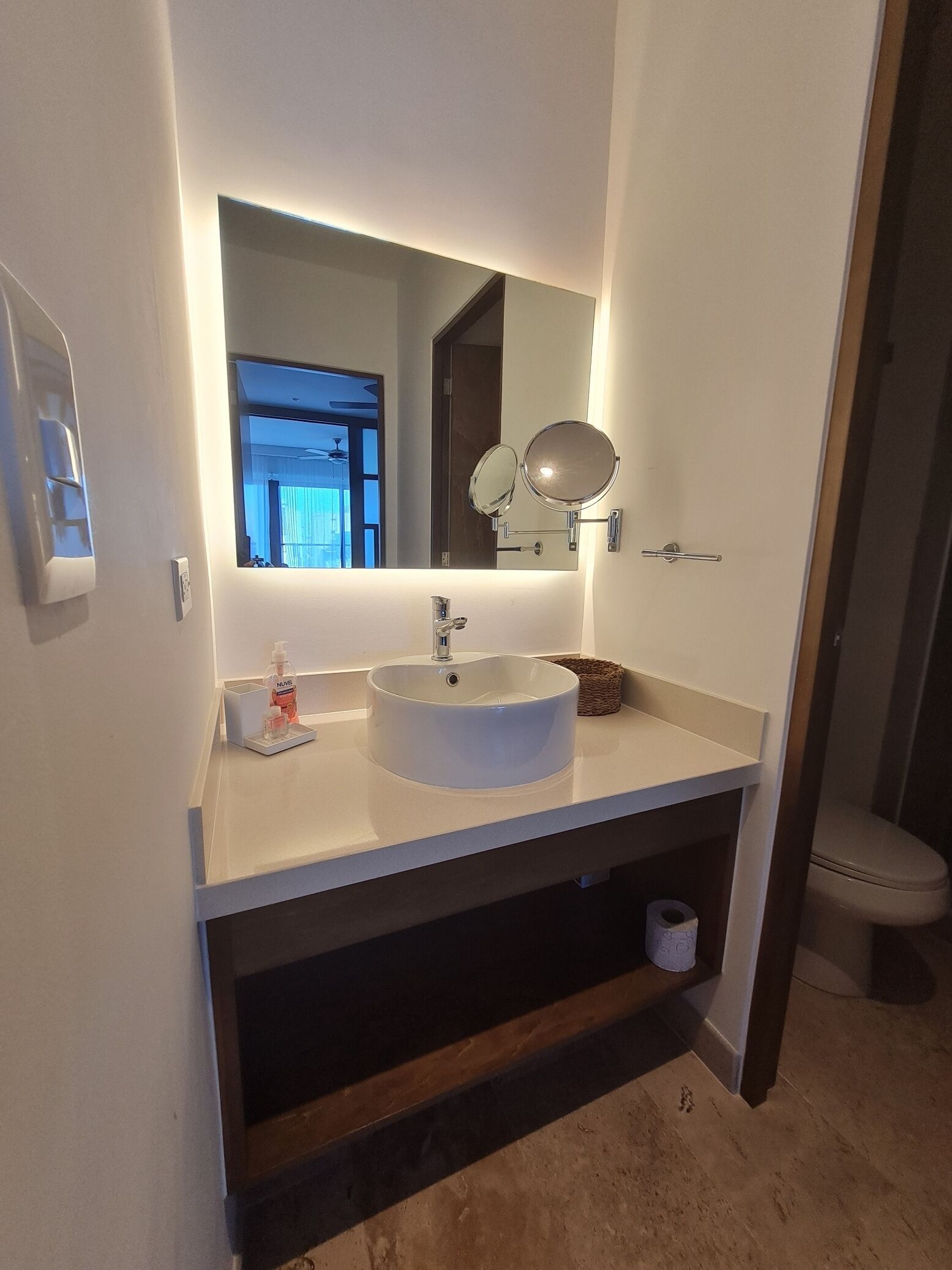 A modern bathroom with a round sink, a mirror, and a toilet.