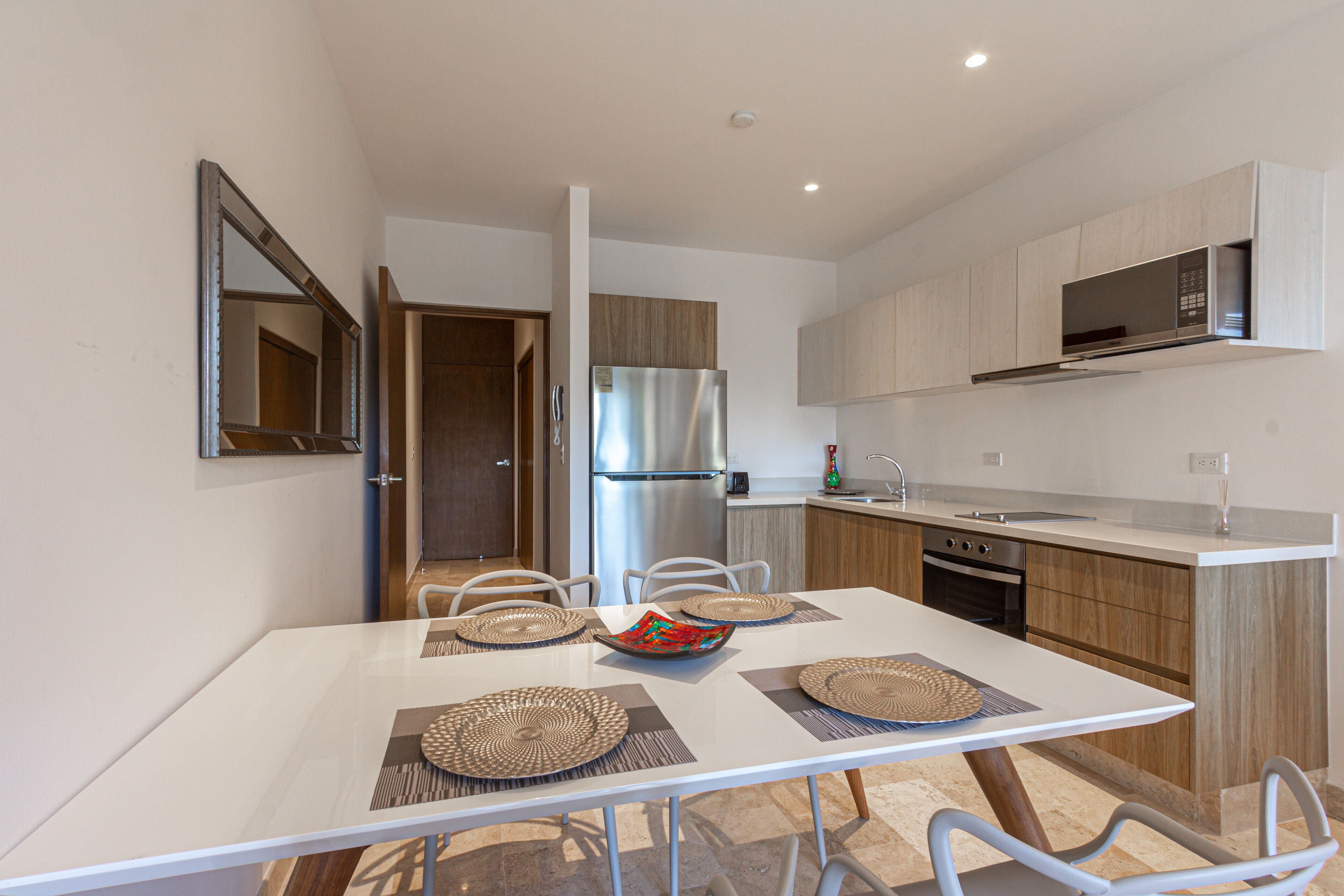 A modern kitchen with a stainless steel refrigerator, wooden cabinets, and a white countertop.