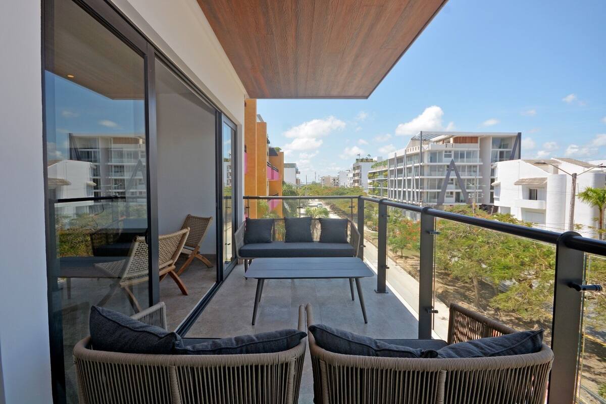 A balcony with wicker furniture and a glass door leading to a room.