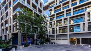 A modern multi-story building with balconies, a commercial space on the ground floor, and a clear sky. - Ipana Apartment Deluxe (Playa del Carmen)