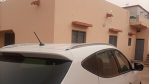 Een witte SUV geparkeerd voor een gebouw met een plat dak en een klein balkon.