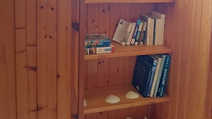 Una estantería de madera con libros y un juego de mesa.