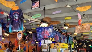 Zona bar con sgabelli, un bancone e diverse insegne e decorazioni.