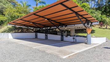 A covered parking area with a metal roof, concrete floor, and a white wall.
