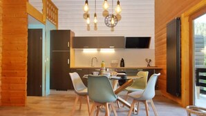 Une cuisine moderne avec des meubles en bois, un coin repas avec des chaises et une grande fenêtre.