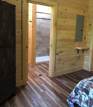 Cozy retreat with a wooden door leading to an outdoor area, a shelf, and a comfortable bed.