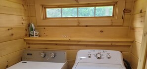 Compact laundry room with two front-loading washing machines and a small shelf for storage.